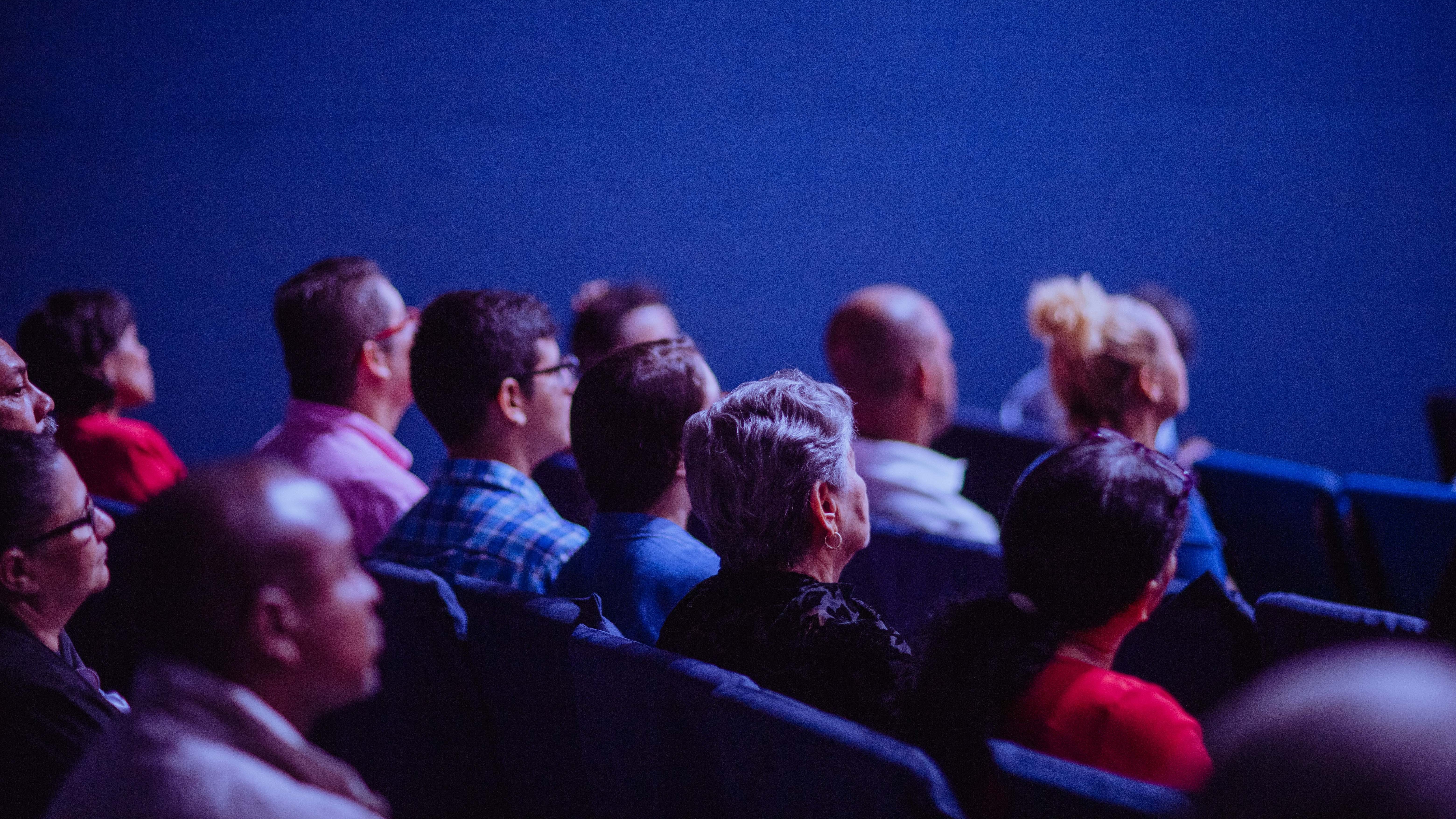 Pessoas sentados em poltronas, representando assistir algum evento